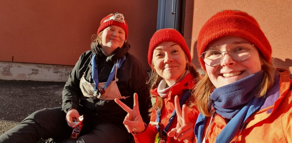 Selfie, jossa kolme hymyilevää naista punaiset pipot päässä.